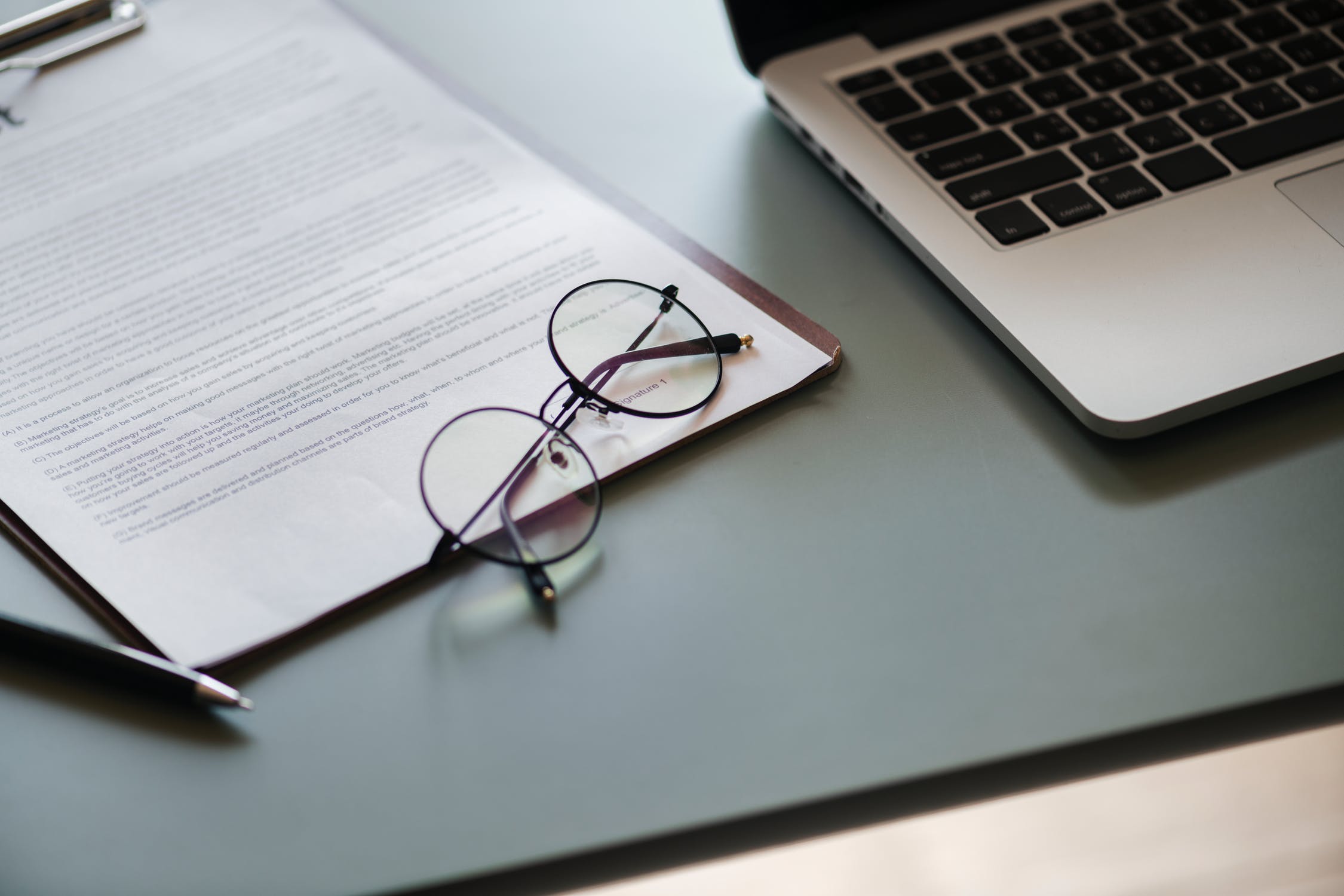 A professional work on desktop with a computer and a pair of glasses.