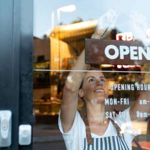 Happy business owner hanging an open sign at a cafe