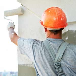 A painter paints white on a wall