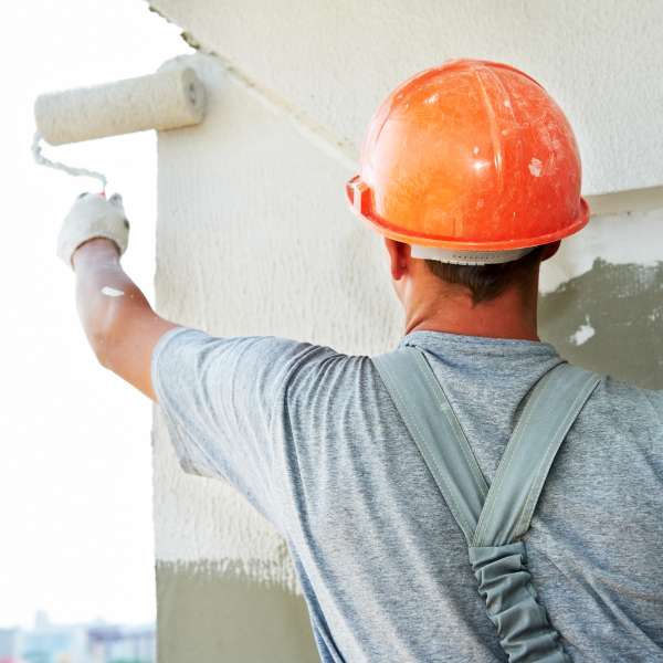 A painter paints white on a wall