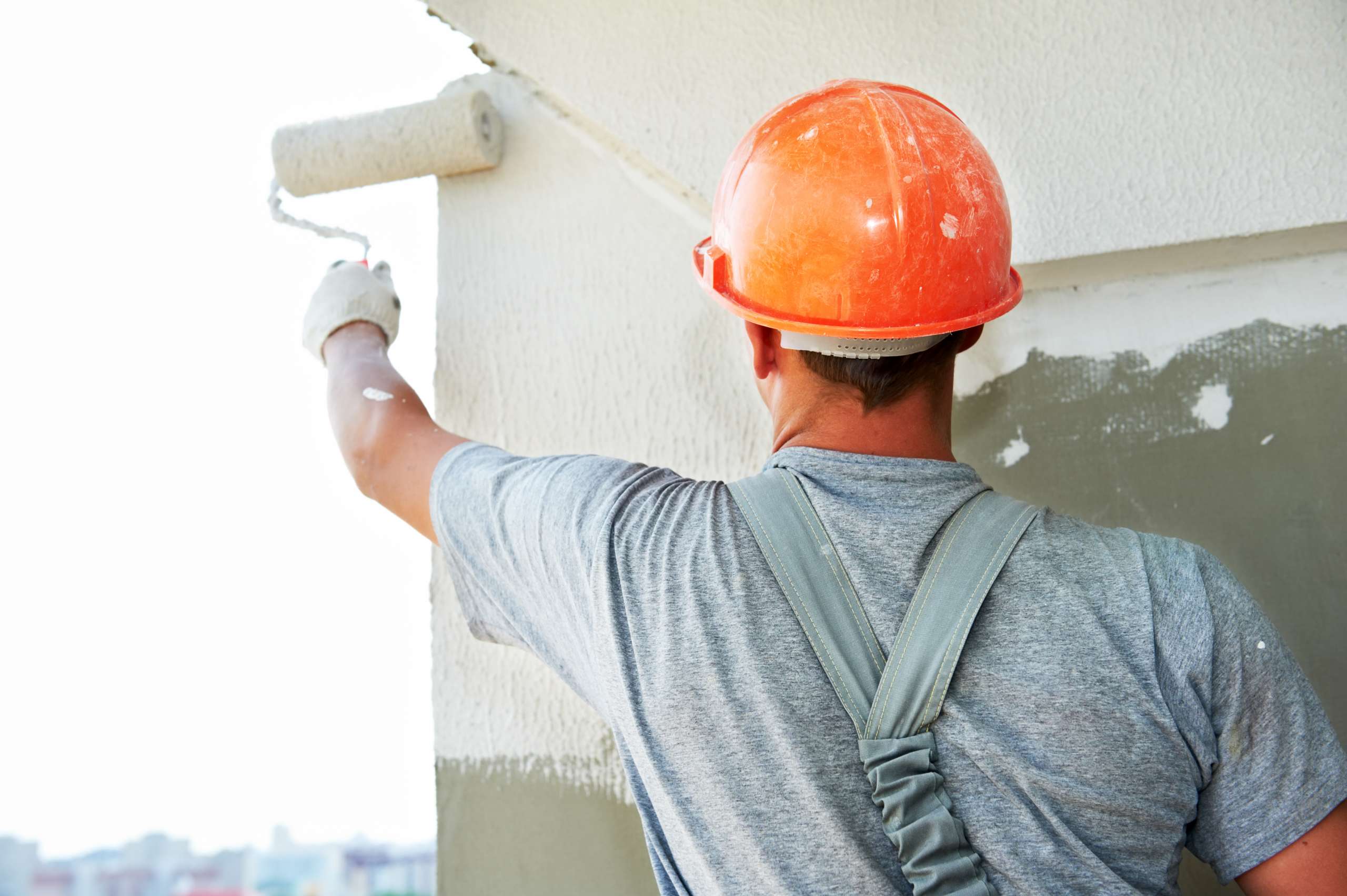 A painter paints white on a wall