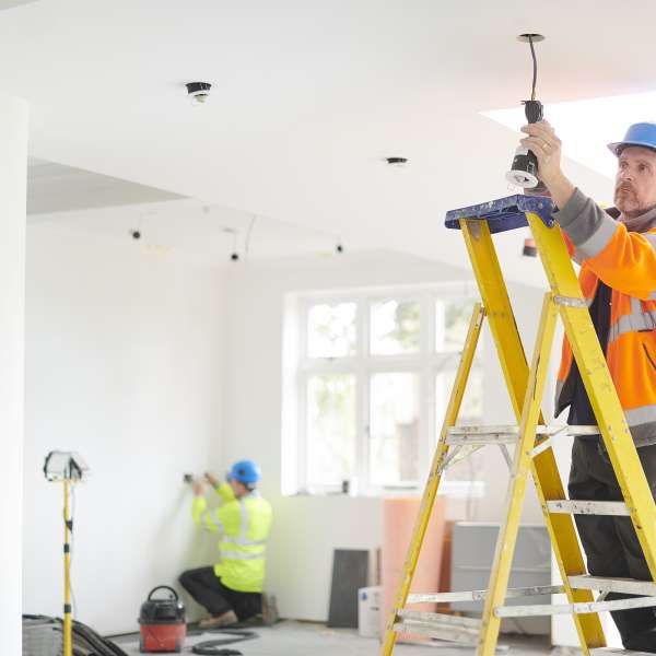 An electrician installs downlights