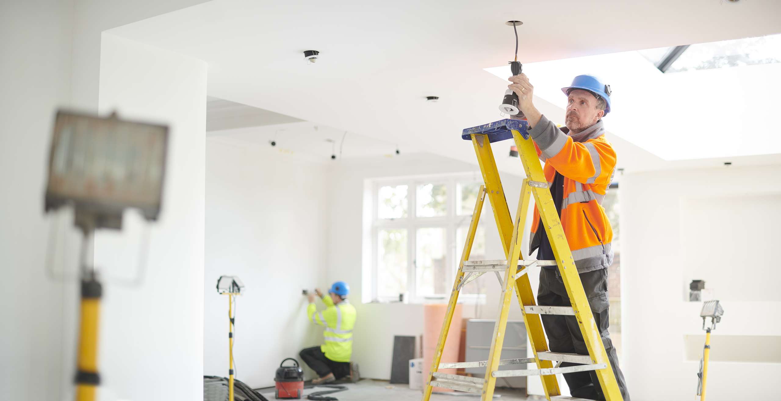 An electrician installs downlights