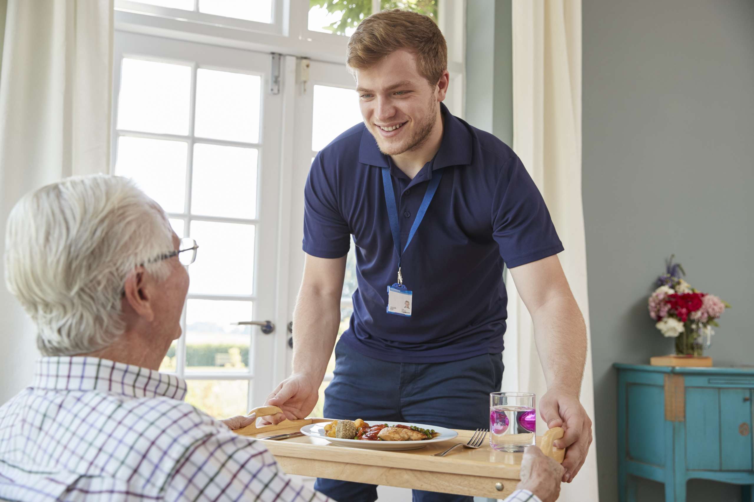 Care worker serving dinner to a senior man at home