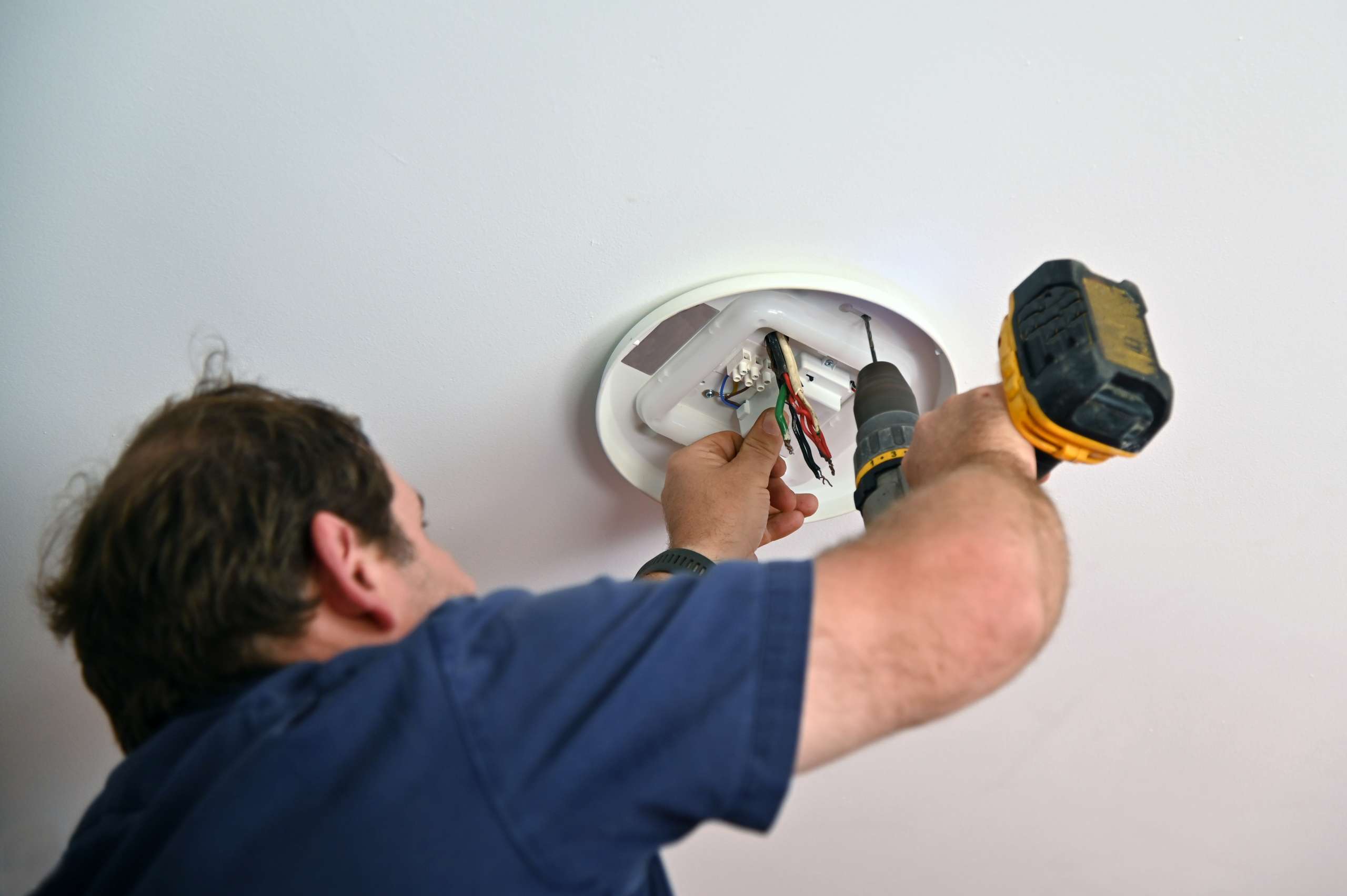 An electrician drilling on ceiling