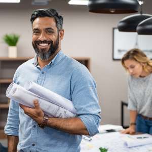 Happy employee holding business plans and blueprints