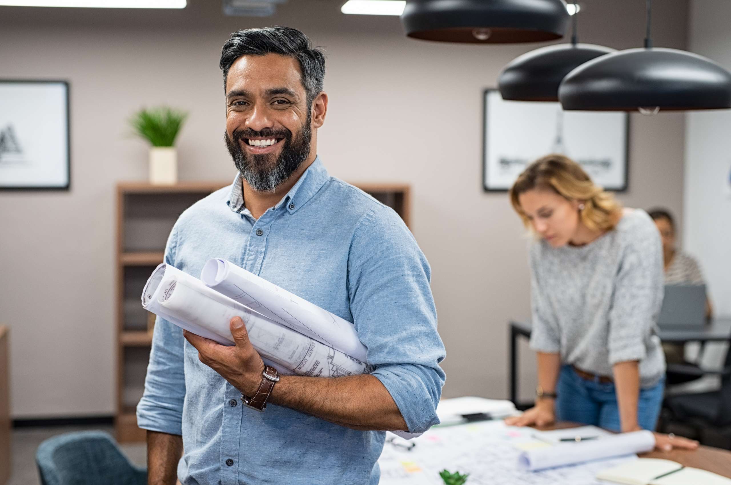 Happy employee holding business plans and blueprints