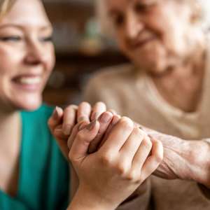 A nurse holing hands with a senior woman.