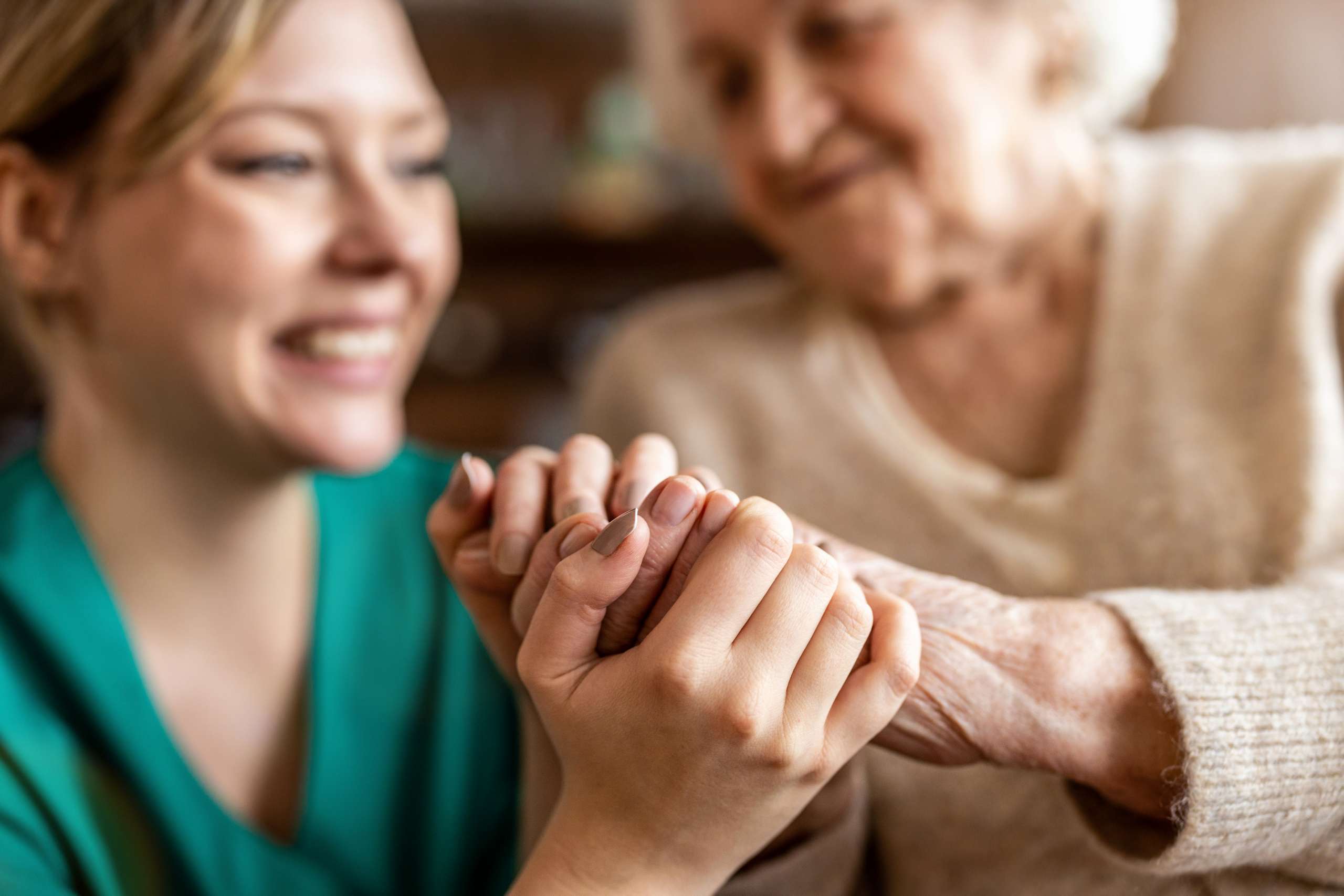 A nurse holing hands with a senior woman.