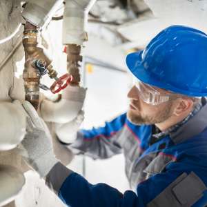 A plumber inspects water pipe valve