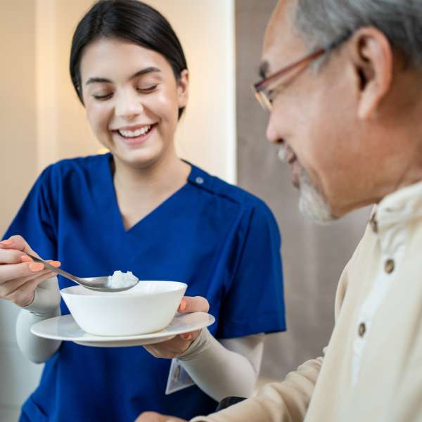 A health care worker serve food to senior patient