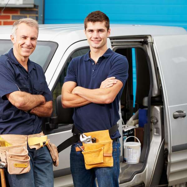 Two plumbers and construction workers with vehicle
