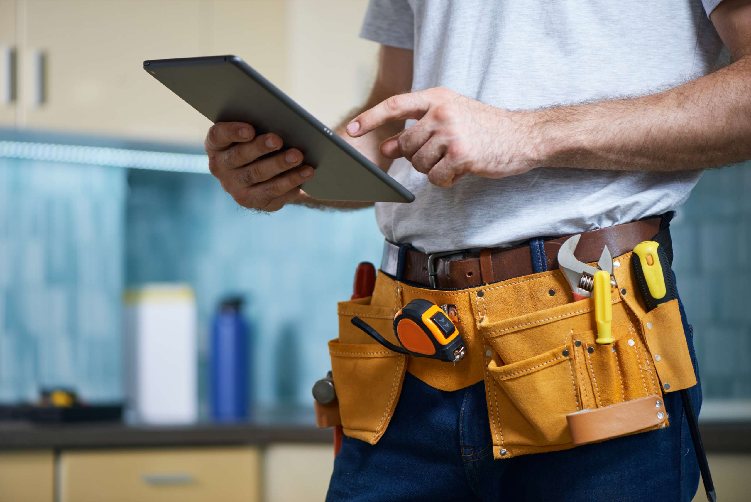 Handyman wearing a toolbelt with tools using digital tablet