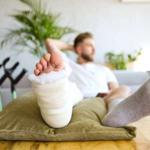 Young man with broken leg resting in bed
