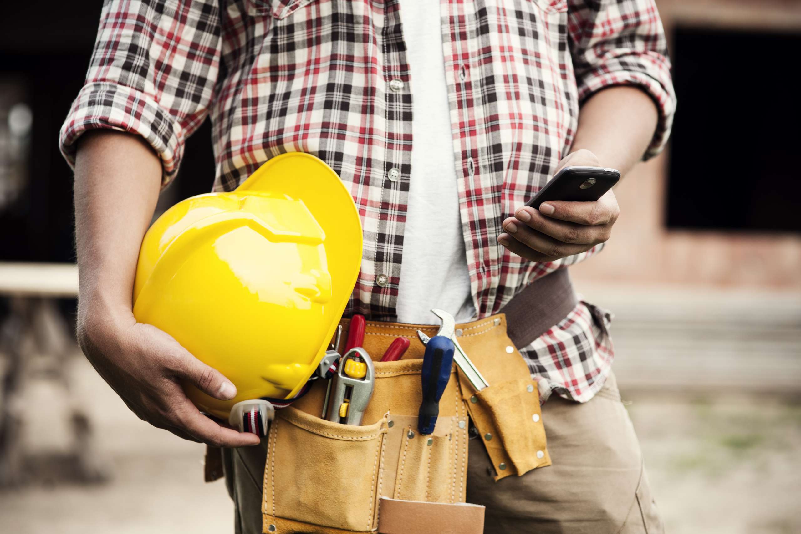 Construction worker typing on a smartphone