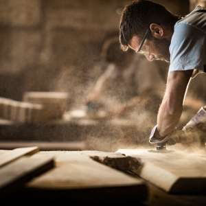 Carpenter using sander while working on a piece of wood.