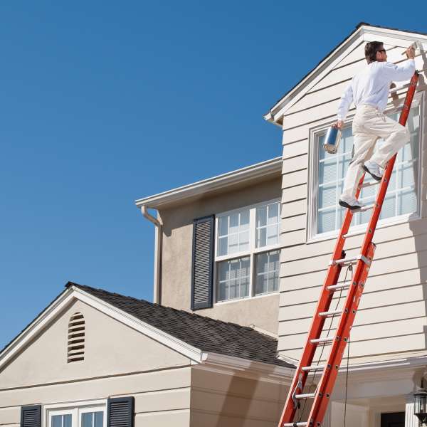 House painter painting house exterior with paint brush