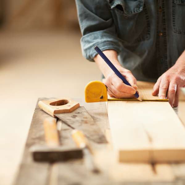 A caprenter measuring a wooden plank