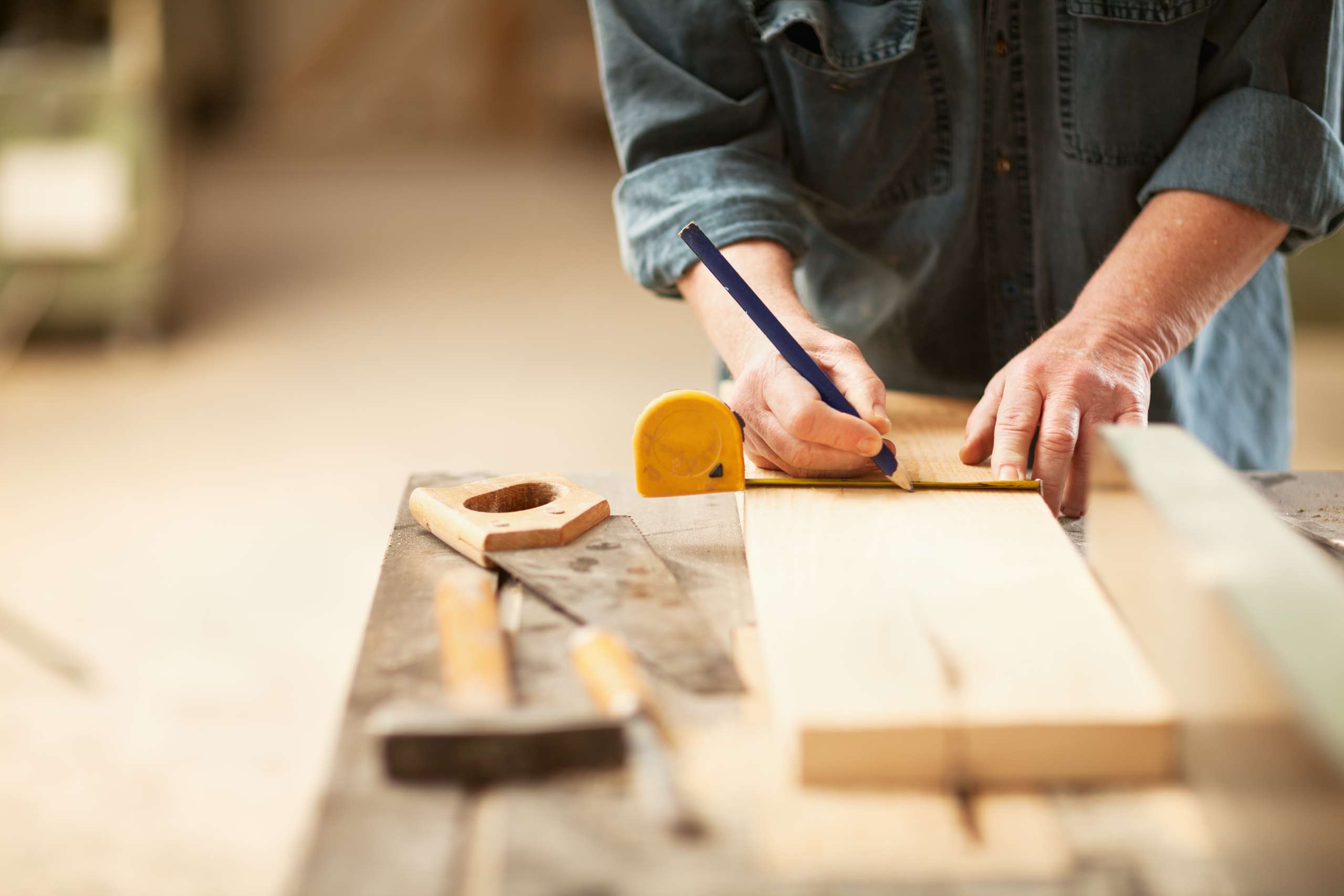 A caprenter measuring a wooden plank