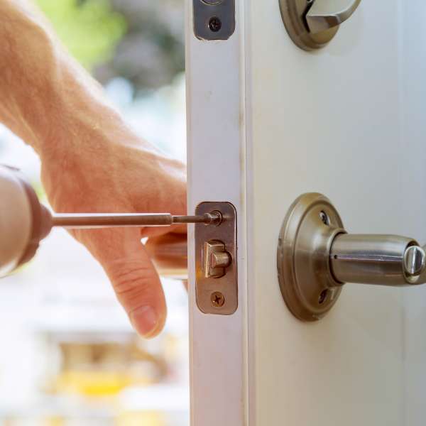 A handyman repairs a home lock.