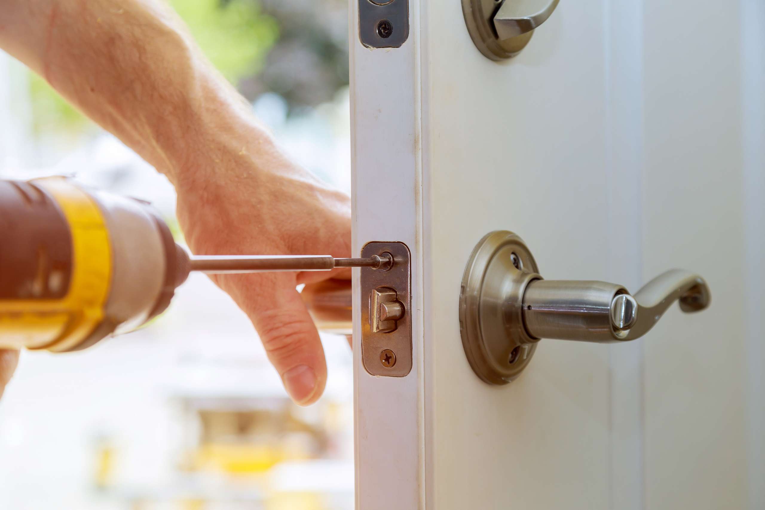 A handyman repairs a home lock.