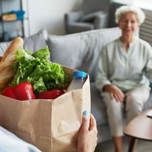 A caregiver delivering groceries to senior woman