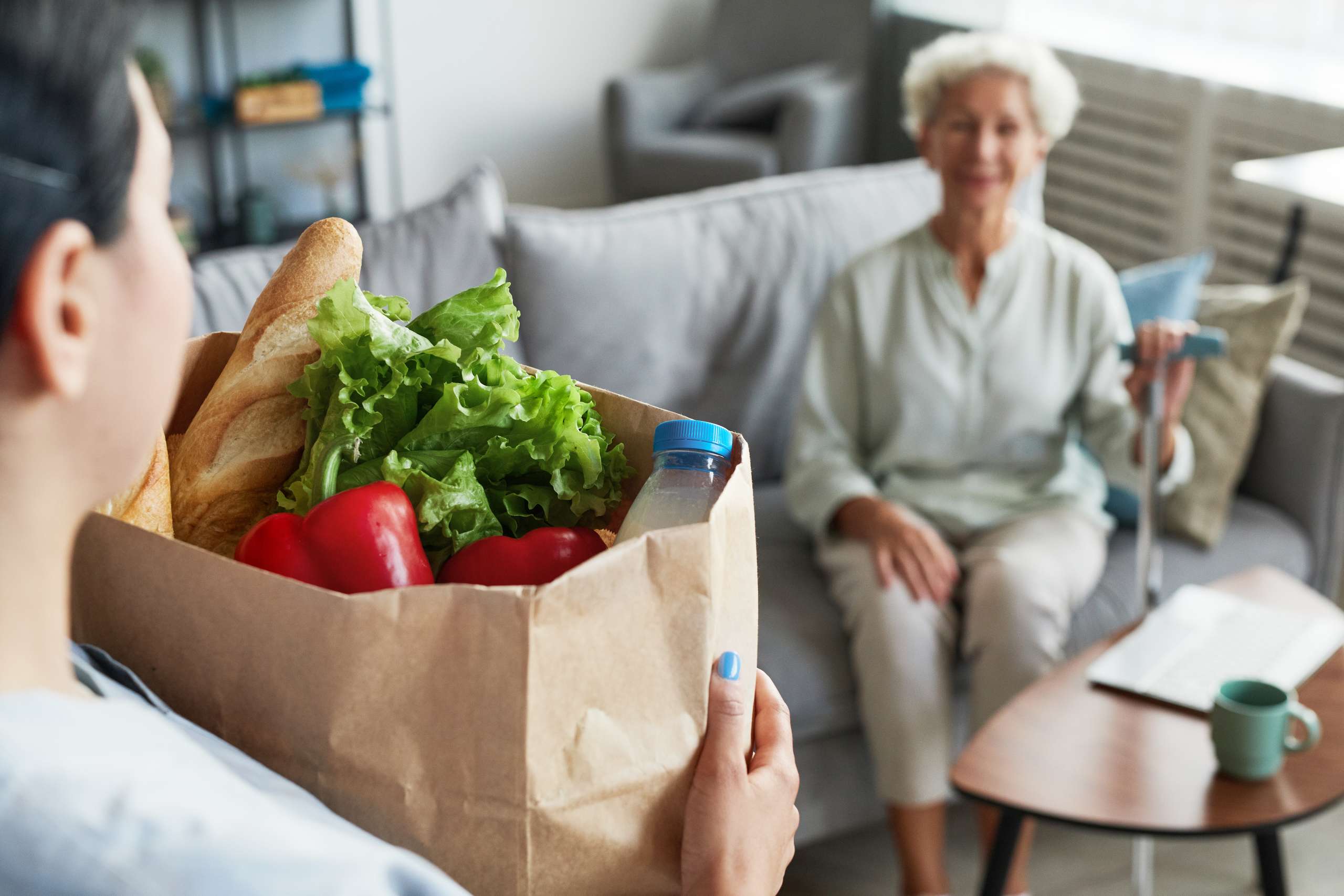 A caregiver delivering groceries to senior woman