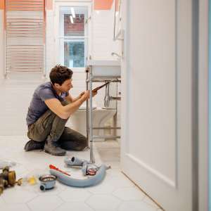 A handyman fixes a leak under the bathroom sink