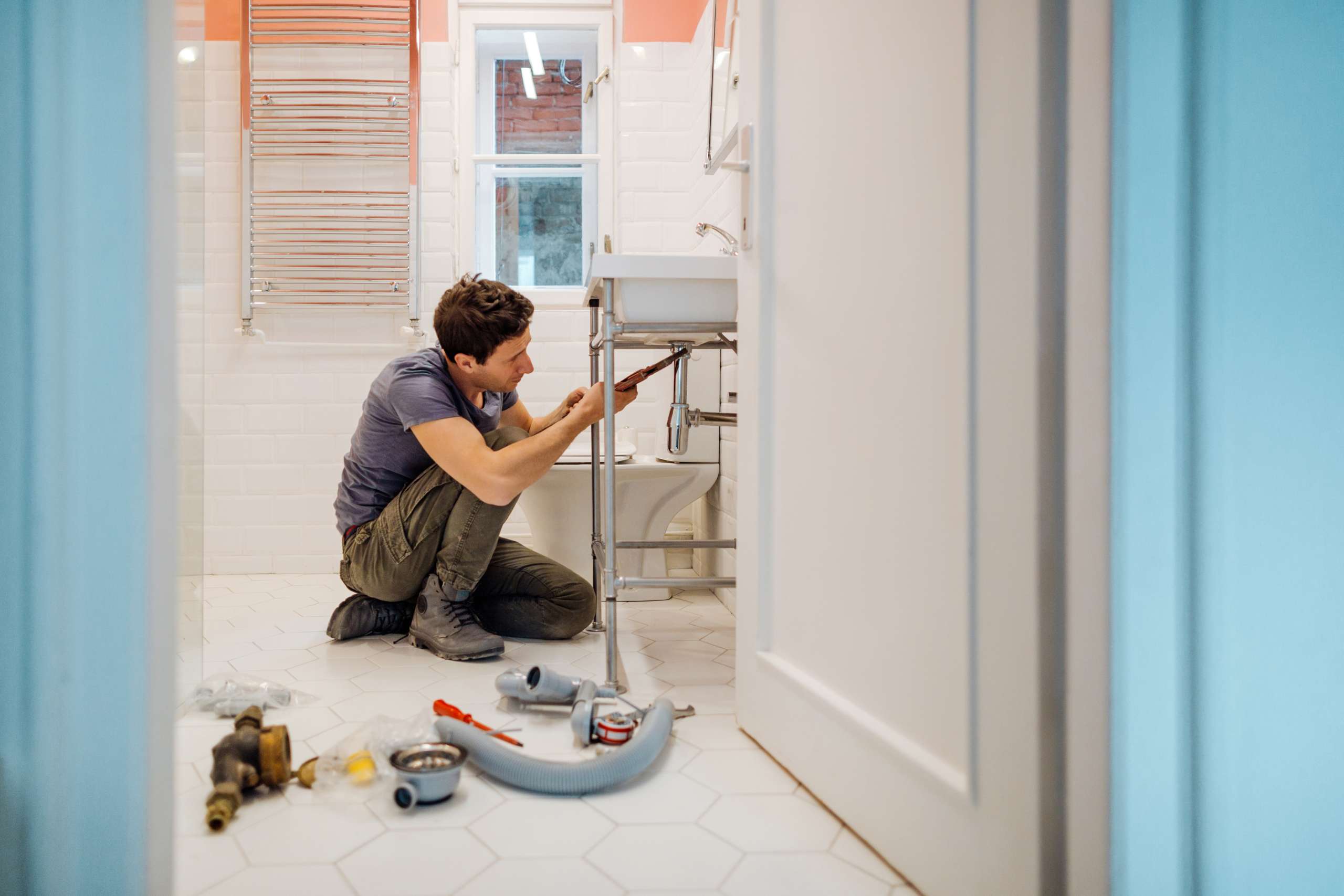 A handyman fixes a leak under the bathroom sink