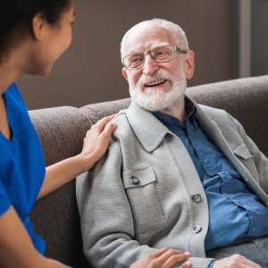 A caregiver talking to happy senior Picture of smiling nurse assisting senior elderly person.