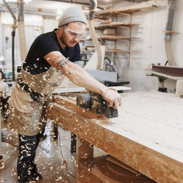 Carpenter working with electric planer on workshop.