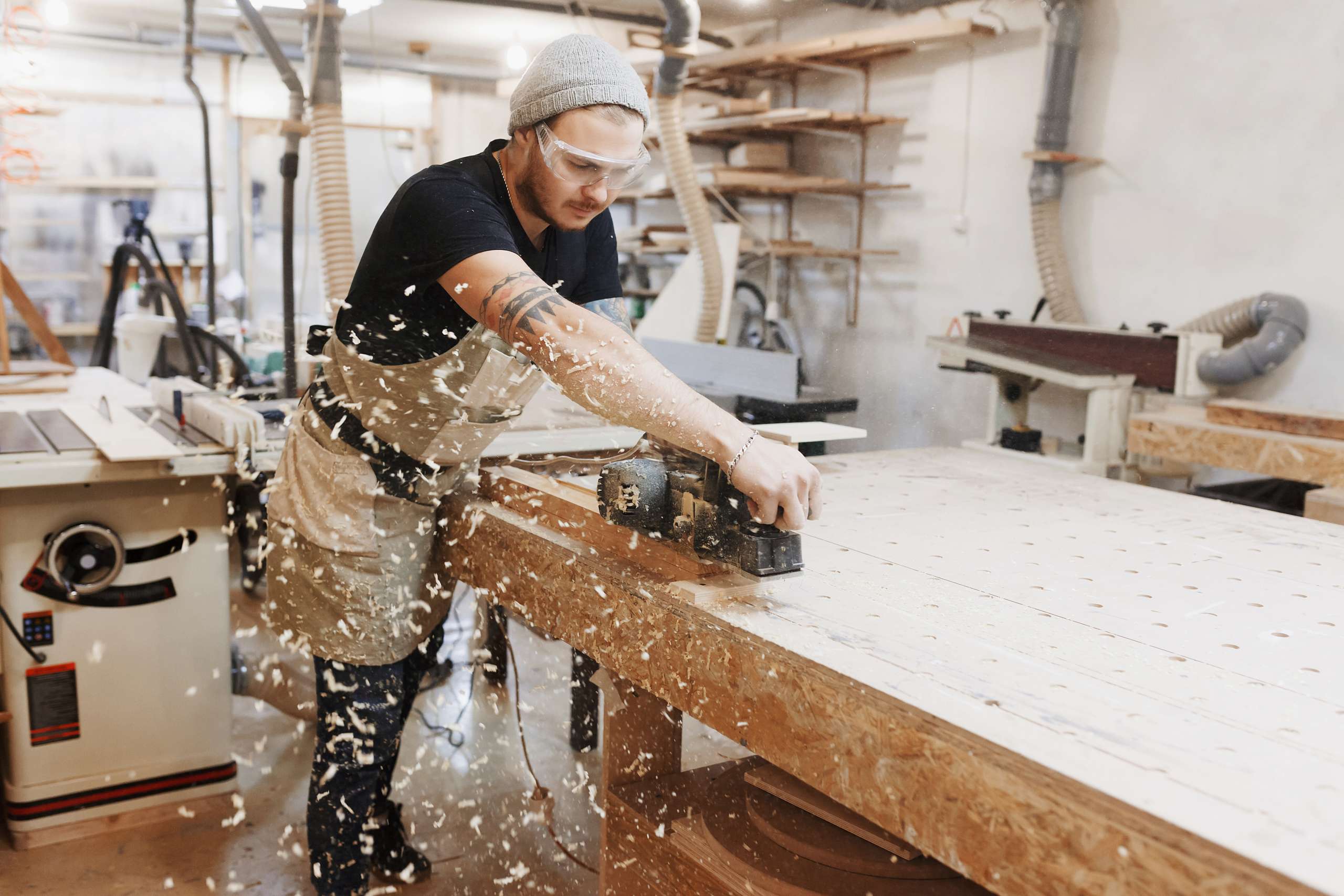 Carpenter working with electric planer on workshop.