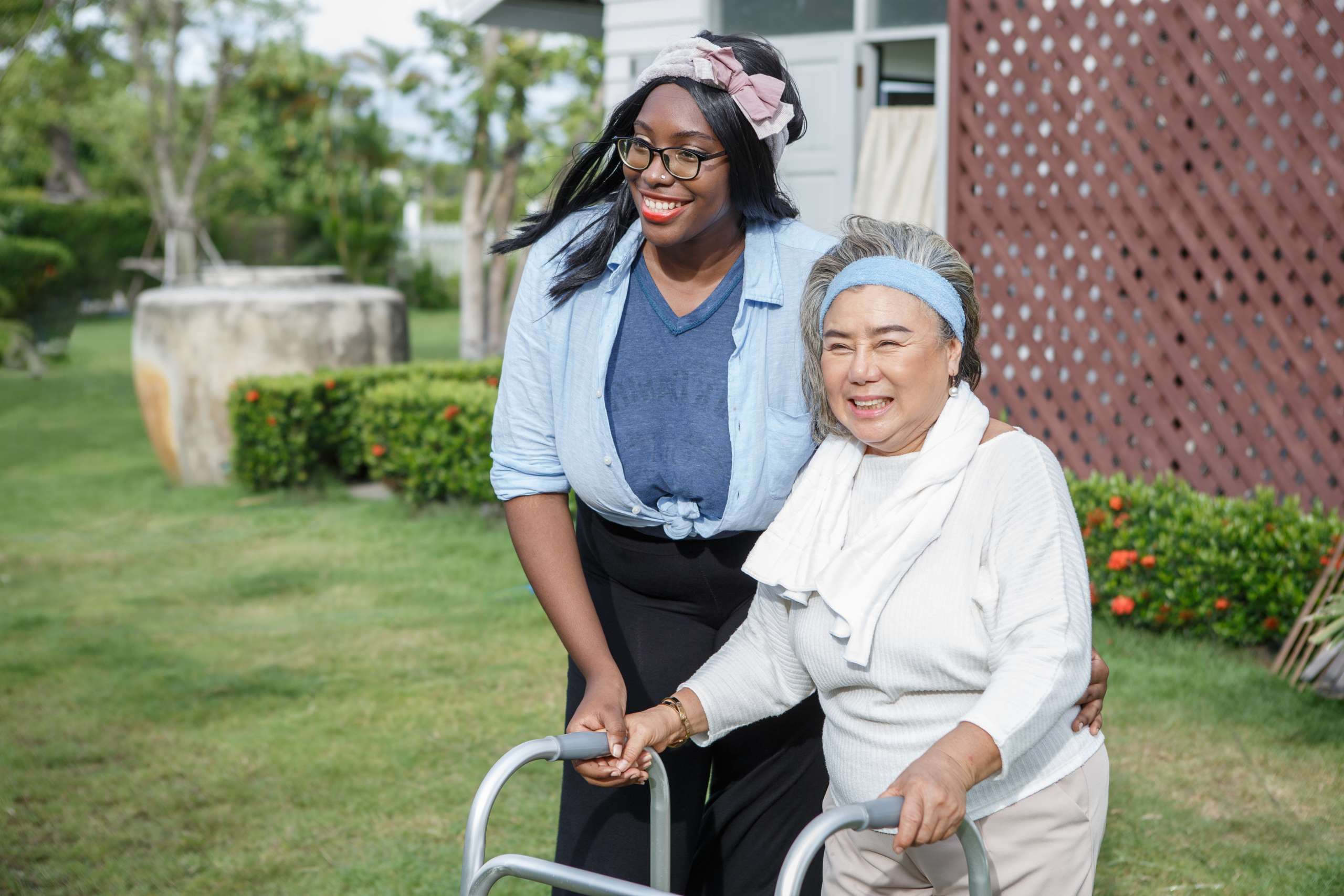 A senior woman with walker and carer in garden at home.