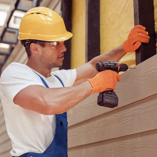 A builder using power drill at construction site