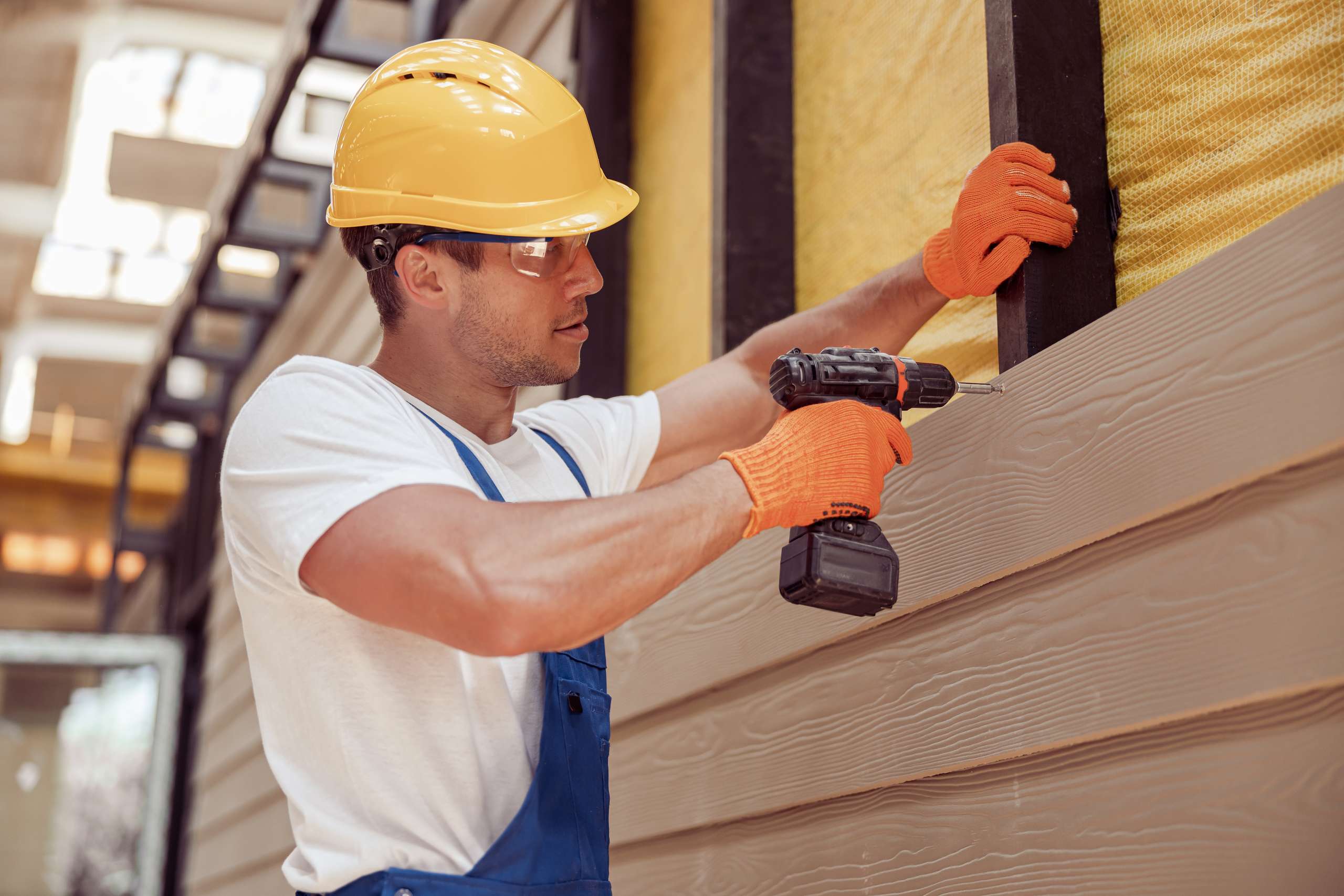 A builder using power drill at construction site