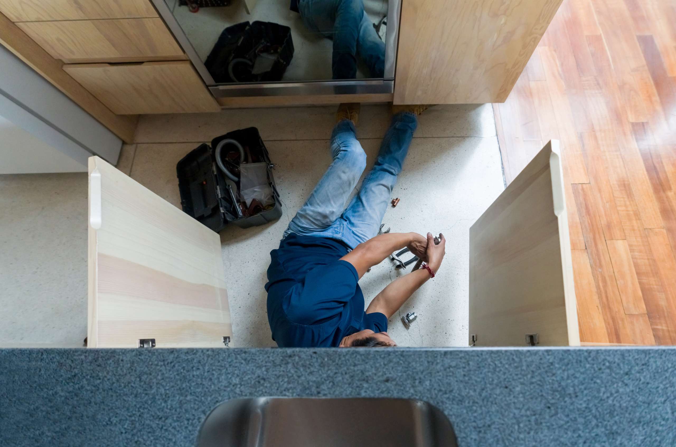 A Plumber fixing a broken pipe in the kitchen