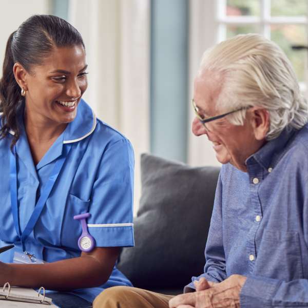 Senior Man At Home Talking To Nurse