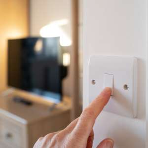 An electrician switching off a room light.
