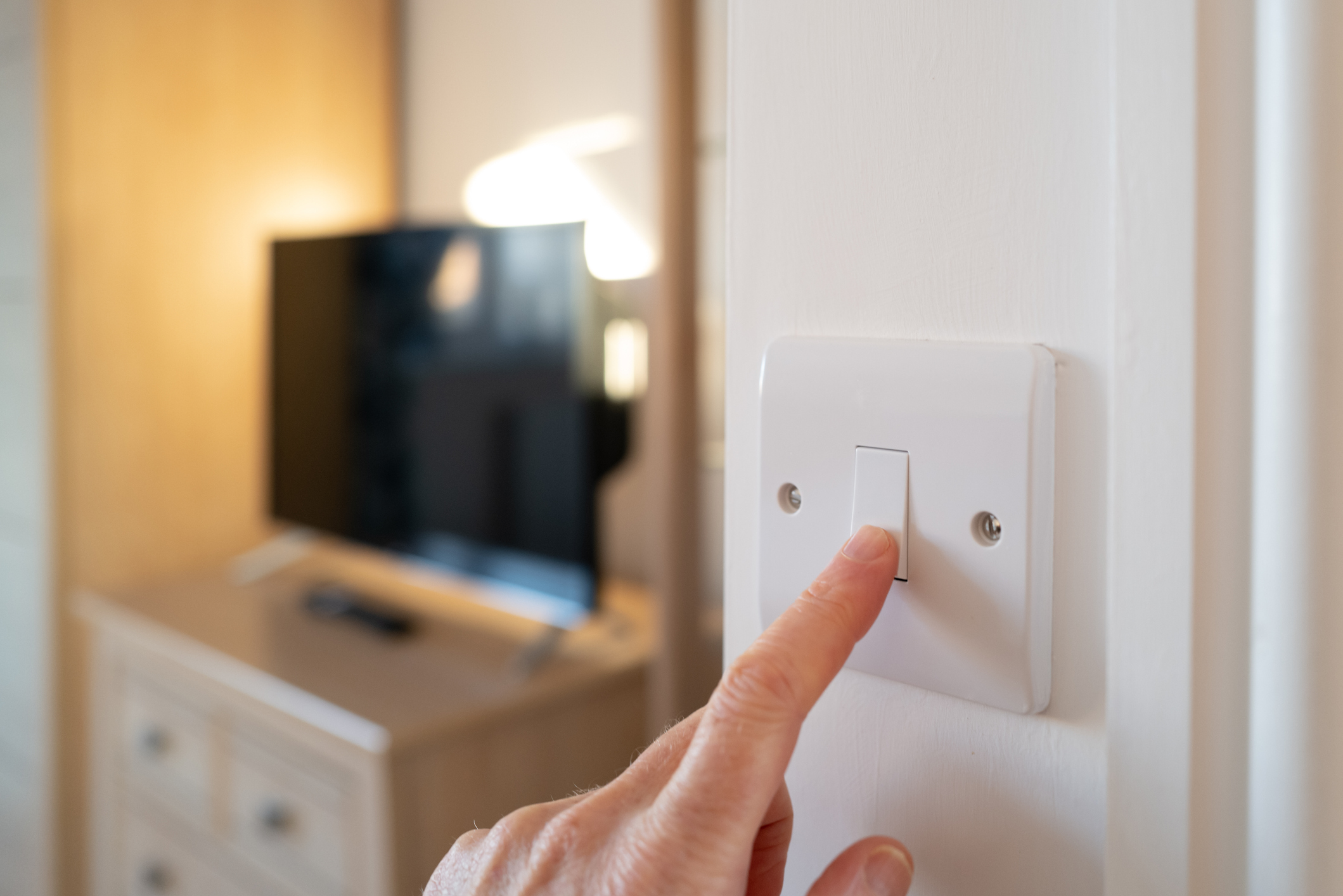 An electrician switching off a room light.