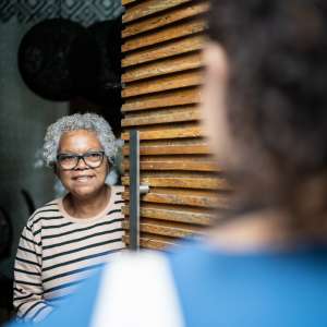 Senior woman open door to healthcare worker arriving at home