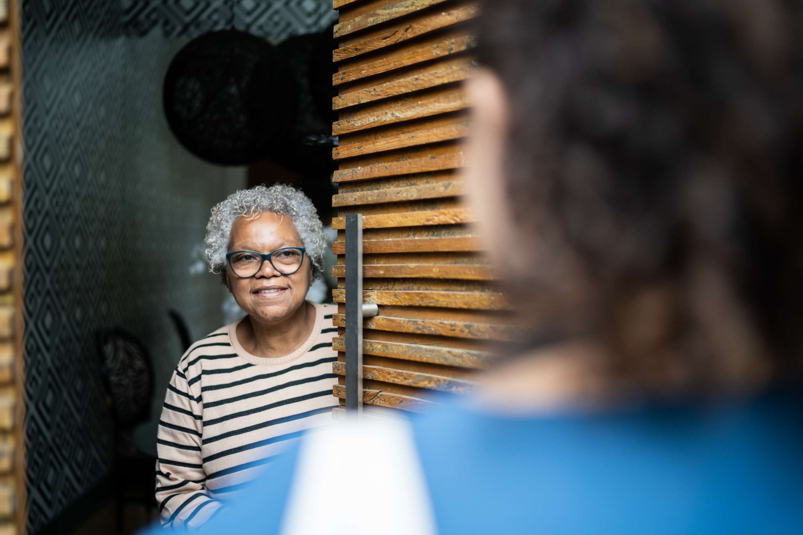 Senior woman open door to healthcare worker arriving at home
