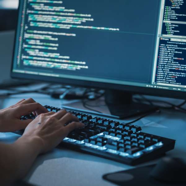 A programmer or software developer typing on the computer.