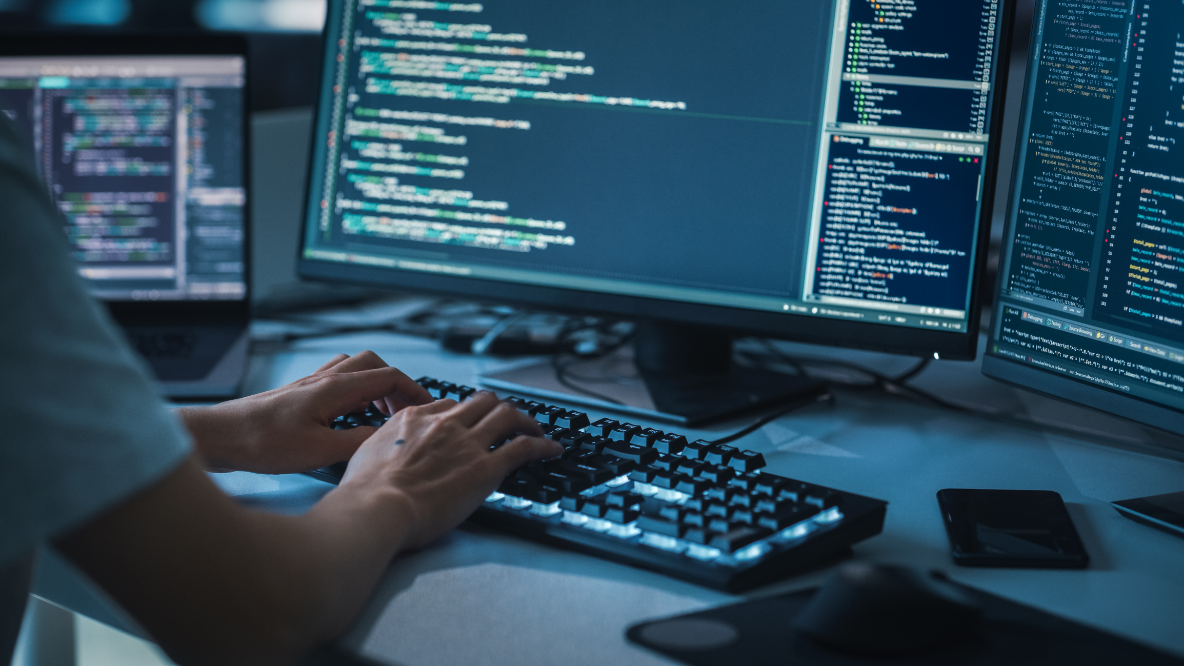 A programmer or software developer typing on the computer.