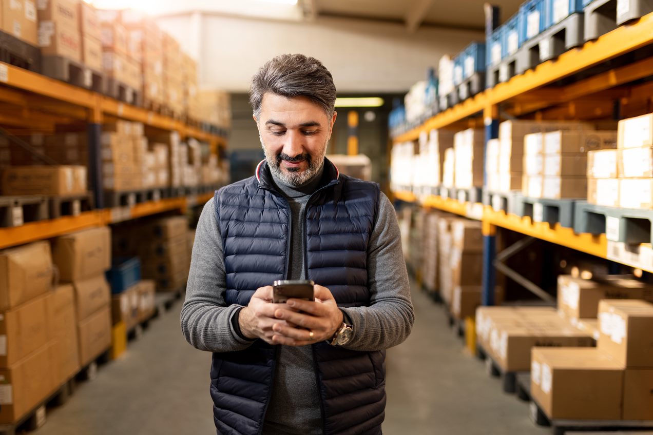 A sole trader standing in inside business looking at his phone