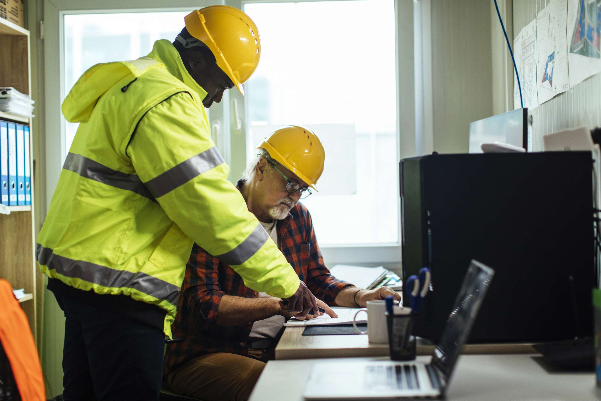 Engineers with the looking at the blueprints in their office.