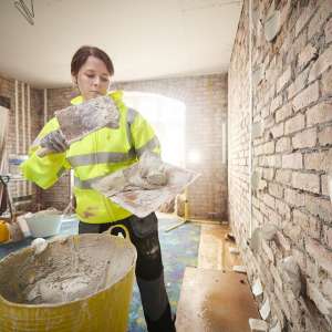 A female plasterer applying drywall adhesive