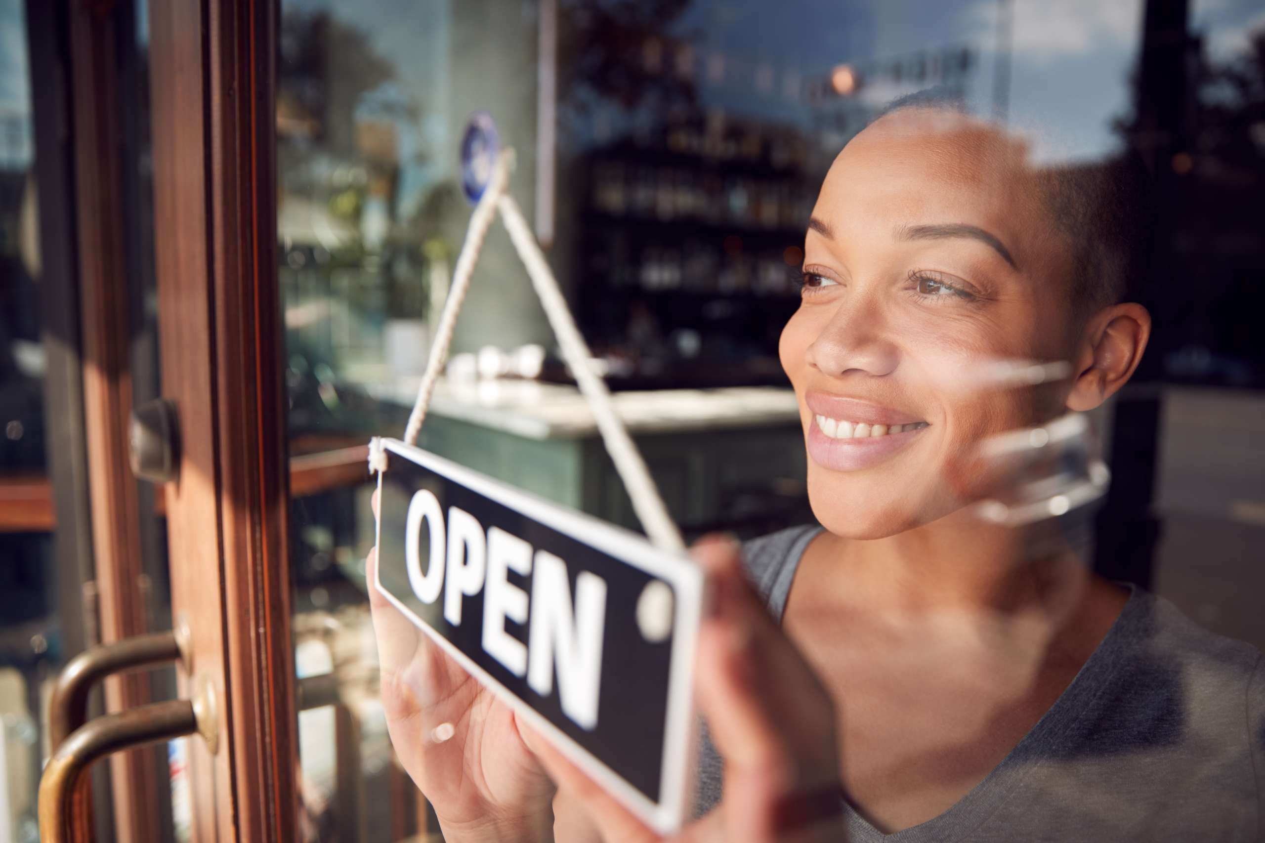 Owner Of Start Up Coffee Shop Or Restaurant Turning Round Open Sign On Door