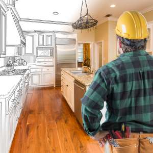 Contractor with hard hat and tool belt looking at custom kitchen