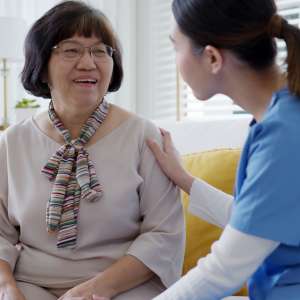 Young woman puts home care hand on senior grandmother shoulder to give support empathy in assisted living