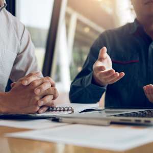 Two businessmen are discussing about the financial budget of the company and sharing the correct analysis.
